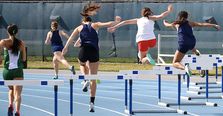 Teen athletes jump over hurdles