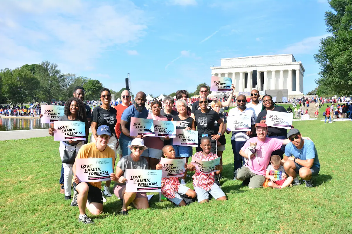 A crowd of families standing in front of the Lincoln Memorial with signs that read, 