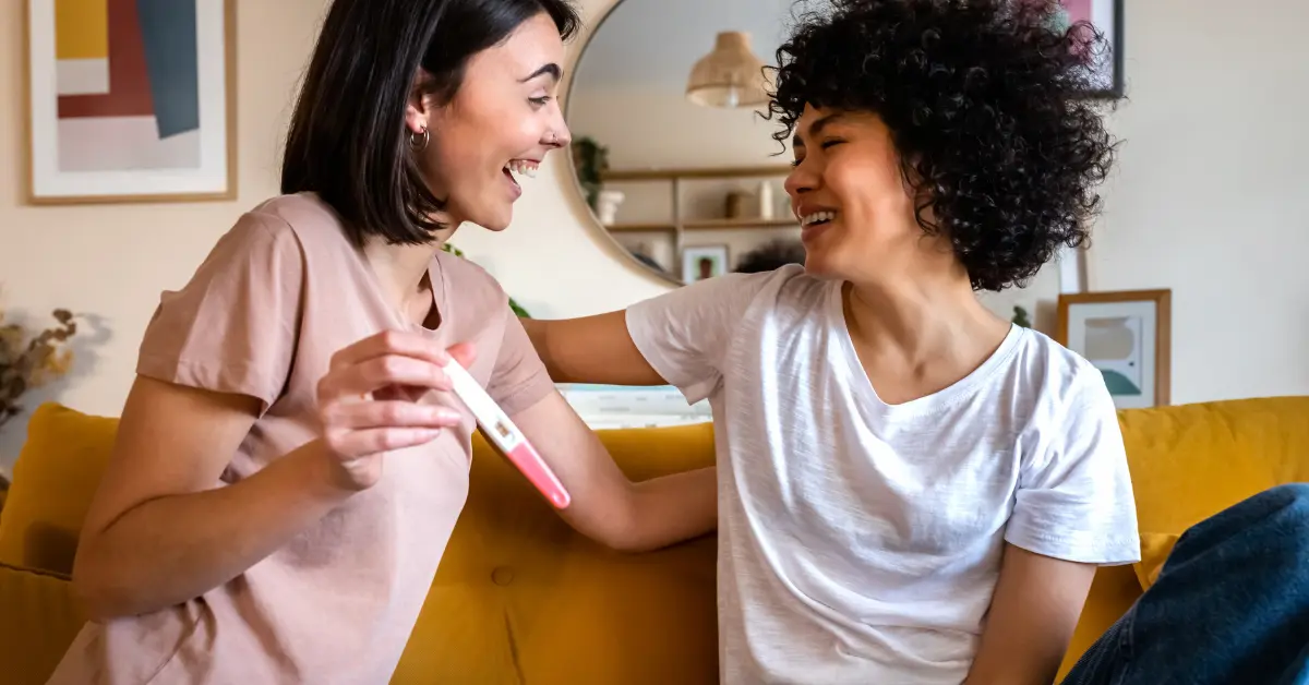 Lesbian moms holding a pregnancy test after pursuing pregnancy with donor sperm