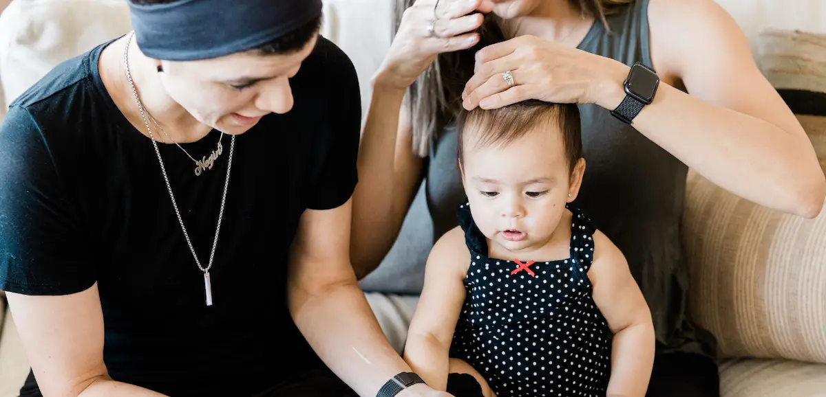 A mom styling her baby's hair with the other mom