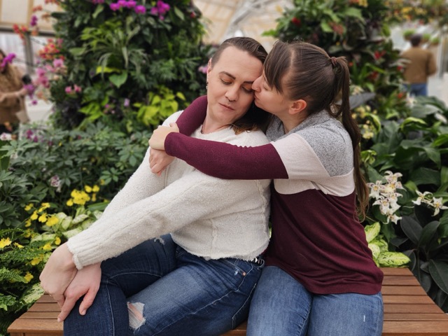 A couple embracing in front of plants