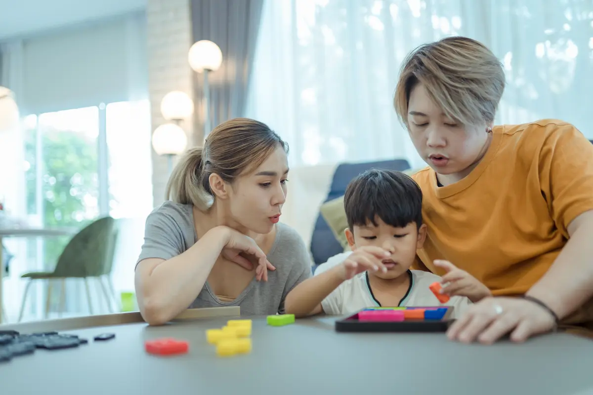 Two moms and one child playing a game indoors