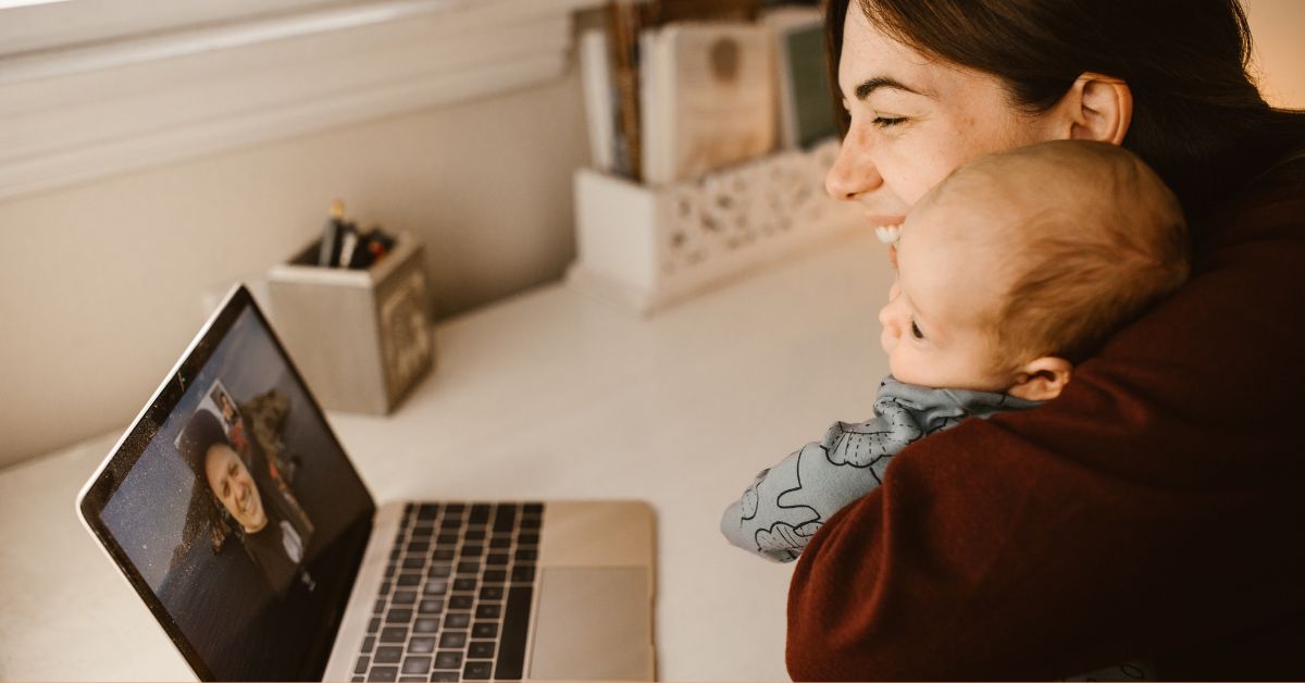 A person with a baby talks to someone else on the computer.